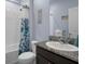 Powder room features a dark wood vanity with granite top, toilet and tub shower with blue accents at 13359 Golden Lime Ave, Spring Hill, FL 34609