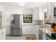 Well-lit kitchen boasting white cabinets, stainless steel fridge, and granite countertops at 138 Edgewater Ter, Dunedin, FL 34698