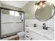 Bright bathroom features a glass shower, modern vanity, and round mirror with a black frame at 2403 Finlandia Ln # 27, Clearwater, FL 33763
