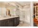 Bright bathroom featuring double sinks, dark wood cabinets, and a glass-enclosed shower at 25325 Welsh Poppy Way, Land O Lakes, FL 34639