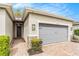 Close-up view of the front entrance with brick pavers, stone accents, and a two-car garage at 25325 Welsh Poppy Way, Land O Lakes, FL 34639
