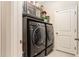 Contemporary laundry area featuring black appliances and upper cabinet storage at 25325 Welsh Poppy Way, Land O Lakes, FL 34639