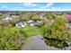 Scenic aerial view of a home by a pond, surrounded by lush greenery and mature trees in a neighborhood at 3944 Sprucewood Pl, Land O Lakes, FL 34639