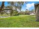 Large backyard featuring green lawn, playground equipment, mature trees and view of lake at 3944 Sprucewood Pl, Land O Lakes, FL 34639