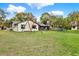 Spacious backyard with swing set, mature trees, green lawn, and exterior view of the home at 3944 Sprucewood Pl, Land O Lakes, FL 34639
