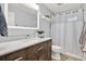 Well-lit bathroom featuring a wooden vanity, modern fixtures, and a clean, white shower curtain at 3944 Sprucewood Pl, Land O Lakes, FL 34639