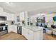 Bright, open kitchen and living area featuring white cabinetry, quartz countertops, and stainless steel appliances at 3944 Sprucewood Pl, Land O Lakes, FL 34639
