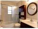 Bathroom with shower and tub combination, dark wood vanity and round mirror at 5155 Kenmore St, Spring Hill, FL 34608