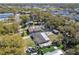 An aerial view shows the home's roof, backyard, sheds, mature trees and surrounding neighborhood in daylight at 200 W Louisiana Ave, Tampa, FL 33603