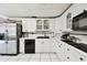 Traditional kitchen featuring white cabinets, black appliances, stainless steel refrigerator, and tile flooring at 200 W Louisiana Ave, Tampa, FL 33603