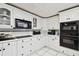Traditional kitchen featuring white cabinets, black appliances, and black and white backsplash at 200 W Louisiana Ave, Tampa, FL 33603