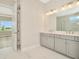 Bright bathroom features a double sink vanity with modern lighting and a view to the yard at 10714 Torchwood Sea Way, San Antonio, FL 33576