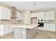 Bright kitchen features white cabinets, stainless steel appliances, large island with quartz countertops and pendant lighting at 10714 Torchwood Sea Way, San Antonio, FL 33576