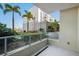 Relaxing balcony with glass railing showcases lush landscaping and swaying palm trees against a blue sky at 111 N 12Th St # 1314, Tampa, FL 33602