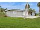 Single-story home with a well-manicured backyard, showcasing lush green grass and mature trees at 112 Rose St, Venice, FL 34293