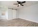 Bedroom featuring wood-look floors, a barn door, and a modern ceiling fan at 112 Rose St, Venice, FL 34293