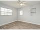 This bedroom offers wood flooring, a ceiling fan, built-in shelving, and two bright, sun-filled windows at 112 Rose St, Venice, FL 34293