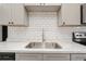 Bright, airy kitchen with stainless sink, marble counters, white subway tile, and gray cabinets at 112 Rose St, Venice, FL 34293