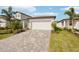 A one-story home featuring an attached two-car garage, a brick driveway, and simple landscaping at 129 Whiteland Bnd, Nokomis, FL 34275