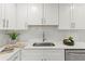 Close up of kitchen featuring a stainless steel sink, marble countertops and stylish white subway tile at 1464 S Evergreen Ave, Clearwater, FL 33756