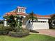 Beautiful two-story waterfront home with a red tile roof, two-car garage, and lush tropical landscaping at 1616 Sand Key Estates Ct, Clearwater Beach, FL 33767