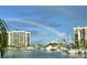 Scenic waterfront view with calm waters, yachts, palm trees, and stunning high-rise condos under a rainbow at 1616 Sand Key Estates Ct, Clearwater Beach, FL 33767
