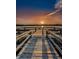 Calm sunset lake view with wooden dock, handrails, and relaxing chair; ideal for serene reflection at 2170 Americus S Blvd # 6, Clearwater, FL 33763