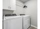 Practical laundry room with modern white washer and dryer, complemented by upper cabinets for organized storage at 2710 Chestnut Creek Pl, Brandon, FL 33510