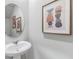 Stylish powder room featuring a pedestal sink, round mirror, and decorative wall art at 2710 Chestnut Creek Pl, Brandon, FL 33510