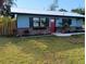 Charming home with a well-maintained lawn, garden beds, and a bright red front door at 402 Mary St, Punta Gorda, FL 33950
