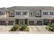 Charming townhomes featuring stucco exteriors, brown garage doors, red shutters, and well-manicured landscaping at 1308 Syrah Dr, Oldsmar, FL 34677
