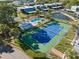 Aerial view showcasing a community pool, tennis court, and surrounding condos with mature landscaping and a scenic pond at 14584 El Paseo Dr, Seminole, FL 33776