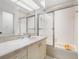 Clean bathroom featuring tiled countertops, updated lighting, a vanity, and a shower-tub combo with glass doors at 14584 El Paseo Dr, Seminole, FL 33776