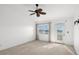 A bright bedroom with large windows, a ceiling fan, neutral carpet, and access to an outdoor balcony at 14584 El Paseo Dr, Seminole, FL 33776