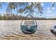A cozy hanging chair with plush pillows overlooking a tranquil lake and natural landscape at 19242 Blount Rd, Lutz, FL 33558