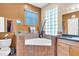 Bright bathroom features a glass block window and a corner bathtub with tile surround at 227 126Th Ave, Treasure Island, FL 33706