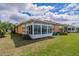 Back exterior view of the sunroom featuring lots of windows allowing ample natural light with a manicured yard at 2313 Nottingham Greens Dr # 2313, Sun City Center, FL 33573