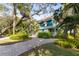 Beautiful blue two-story home with lush landscaping, mature trees, and a paved driveway at 26 W Orange St, Tarpon Springs, FL 34689