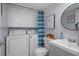 Bathroom with vanity, toilet, and washer/dryer, complemented by stylish blue striped shower curtain at 2612 6Th Ct, Palm Harbor, FL 34684