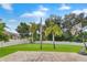 Expansive backyard featuring lush green grass, palm trees, brick patio, basketball hoop, and a privacy fence at 3018 N 164Th Pl, Clearwater, FL 33760