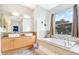 Modern bathroom with double sinks, granite countertop, soaking tub, and a window with a view at 3018 N 164Th Pl, Clearwater, FL 33760
