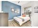 Bedroom with a blue accent wall, modern decor, a full bed, and plenty of natural light at 3018 N 164Th Pl, Clearwater, FL 33760