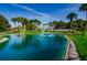 A scenic view of the community pond, complete with a water fountain, palm trees, and the community sign at 3220 Braemar Ter, Palm Harbor, FL 34684