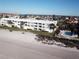 Beachside condo building with white facade, metal roof, and manicured lawn near palm trees and pool, offering ocean views and coastal living at 3400 Gulf Blvd # 304, Belleair Beach, FL 33786