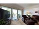 Bright living room featuring a sliding glass door to the balcony, television, and comfortable seating at 3400 Gulf Blvd # 304, Belleair Beach, FL 33786
