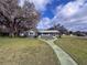 Inviting home featuring a well-manicured lawn and quaint walkway under a partly cloudy sky at 38055 Avion Dr, Zephyrhills, FL 33542