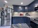 Corner kitchen view highlighting stainless steel refrigerator and navy custom cabinets at 38055 Avion Dr, Zephyrhills, FL 33542