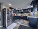 Modern kitchen with stainless steel appliances, navy cabinets, and stylish wood-look tile floors at 38055 Avion Dr, Zephyrhills, FL 33542