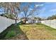 Large back yard with white fence, mature tree, slide, and patio at 415 Maplewood Cir, Oldsmar, FL 34677