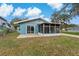 View of the home's backyard, featuring a screened-in porch and a grassy lawn at 4638 Heavens Way, New Port Richey, FL 34652